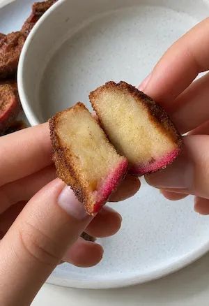 Air fryer apple fry snapped in half showing the soft cooked apple inside its crisp cinnamon sugar coating