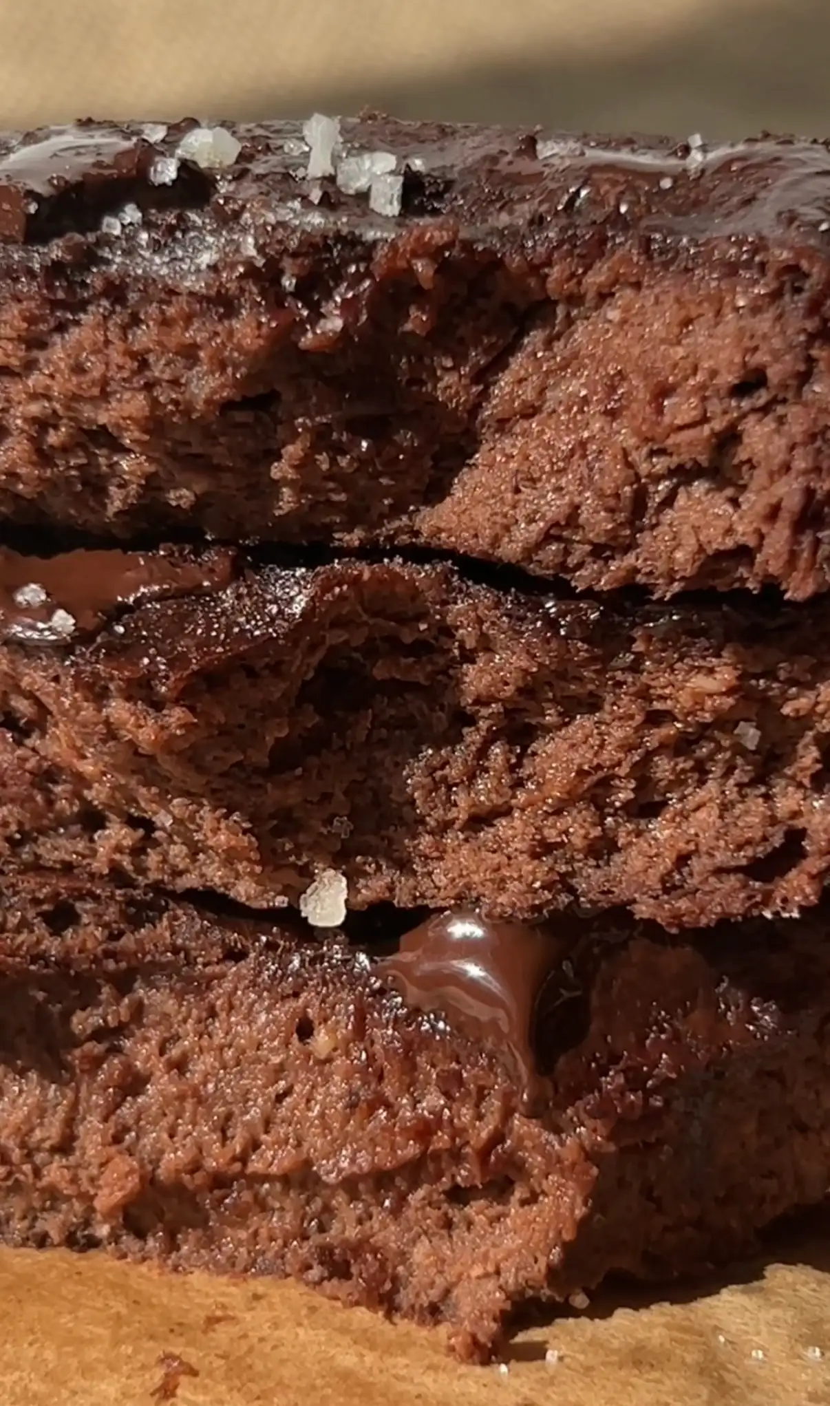 Fudgy 3 ingredient banana brownies stacked and broken open showing a gooey melted chocolate centre, topped with sea salt flakes