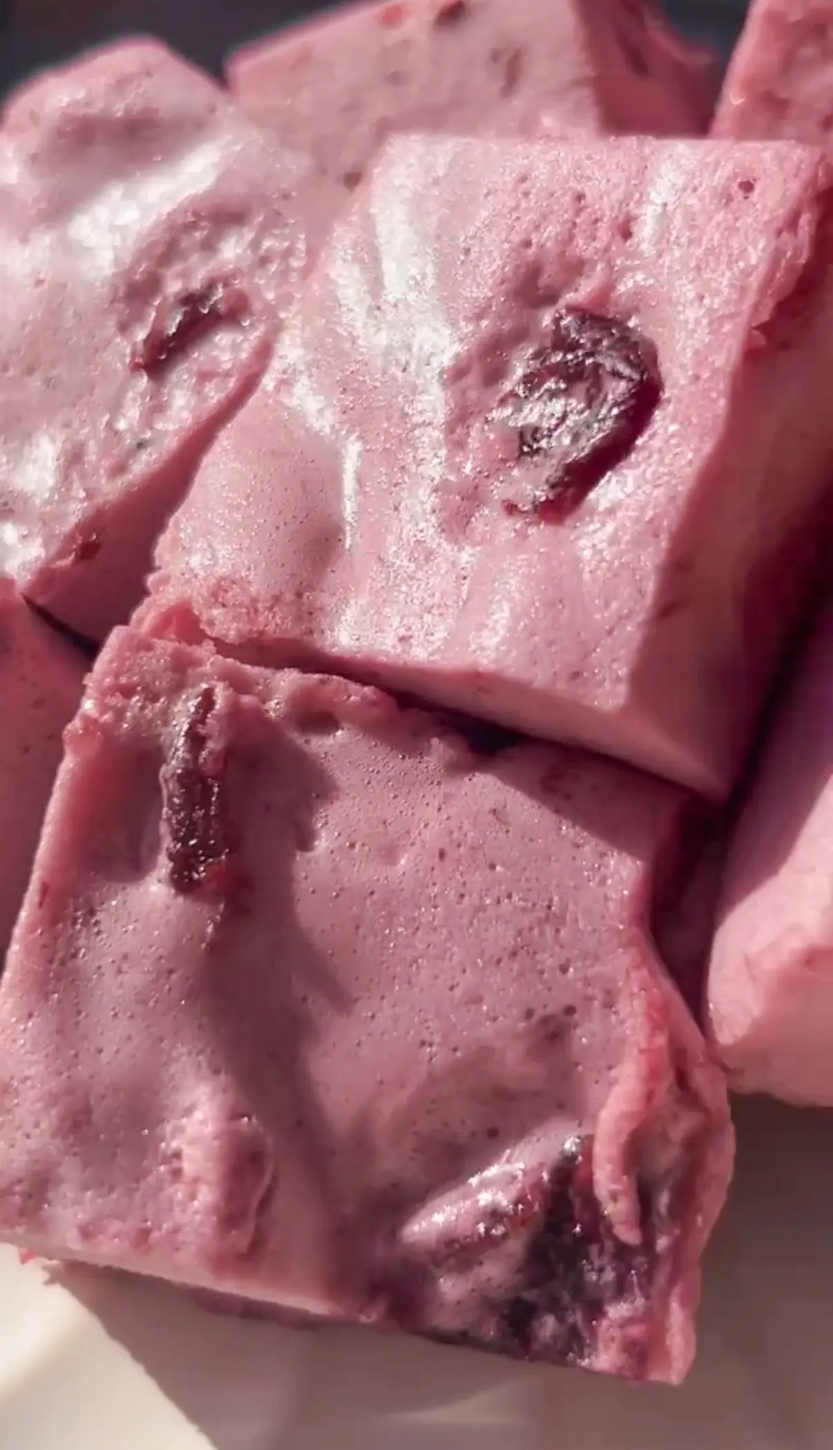 Close-up of sliced pink cherry marshmallow squares stacked together, showing bits of cherry inside the fluffy texture