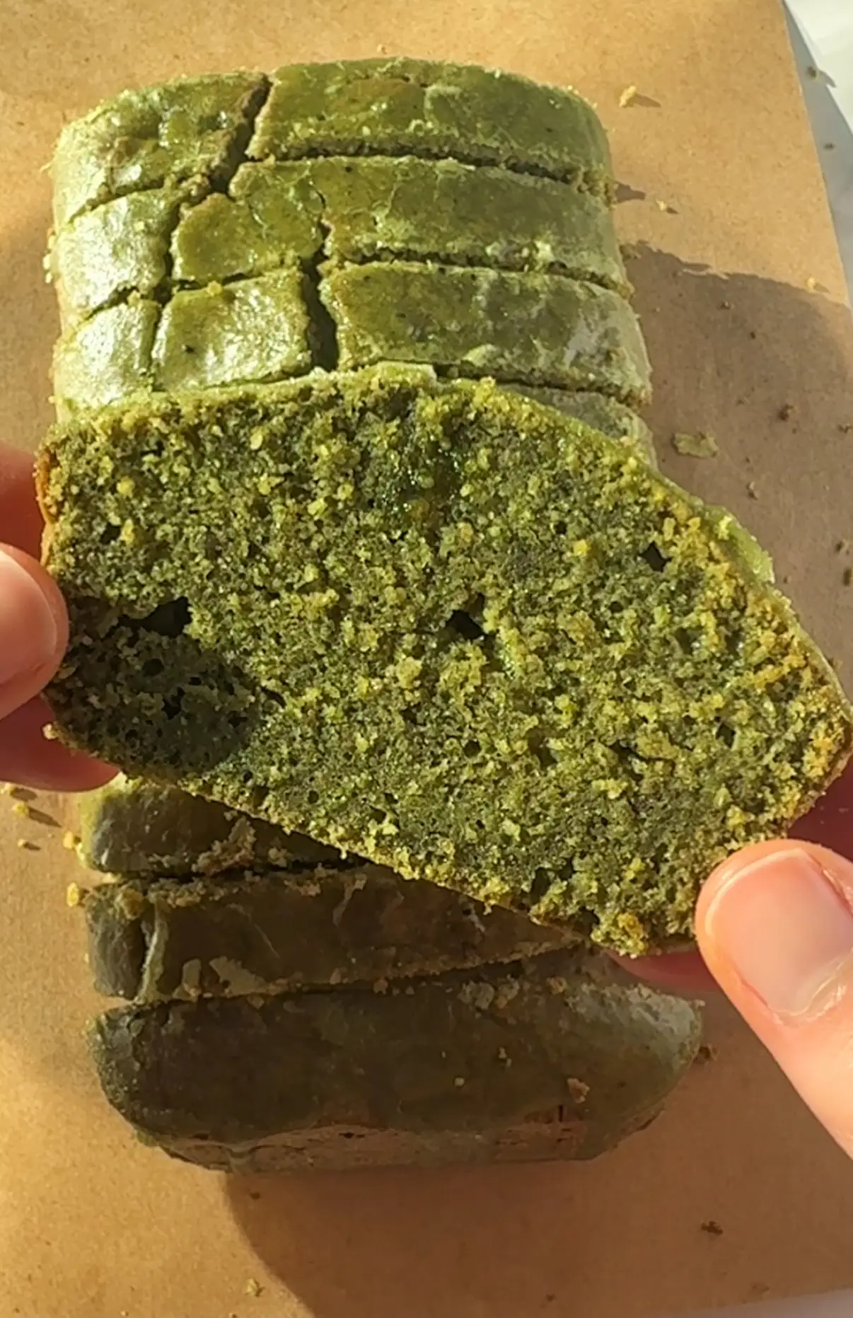 Mini matcha loaf cake sliced on a white surface with matcha icing drizzled on top